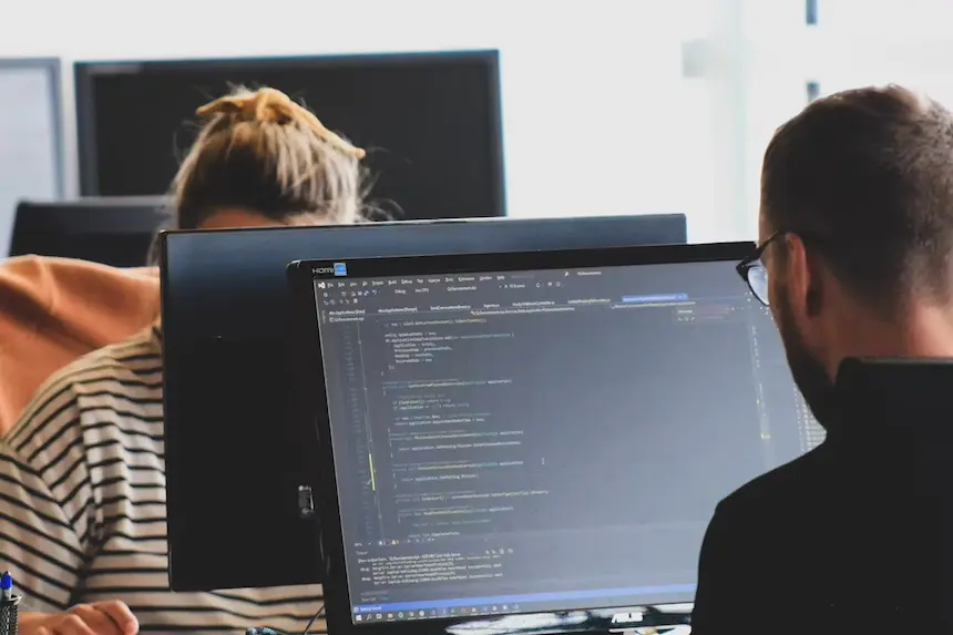 2 people sitting in front of computer mointors doing web support