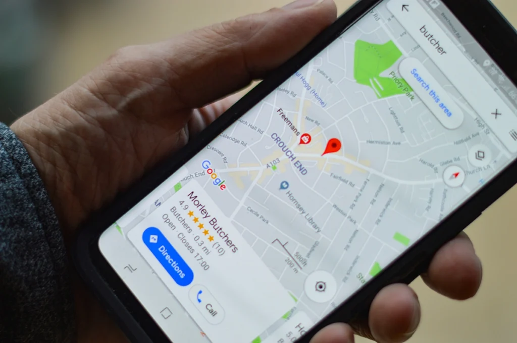Image of a person holding a phone, looking at a google business listing on google maps.