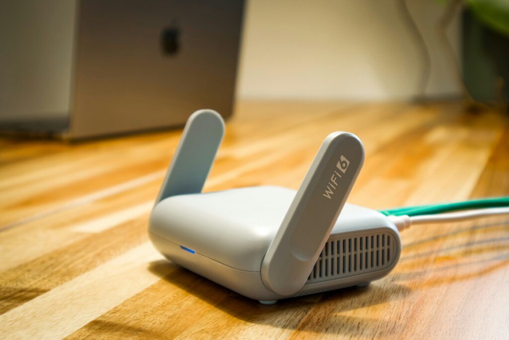 A wireless access point on a wood table. A laptop sits behind it.